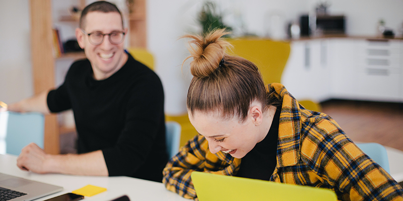 Two people on laptops laughing during a hackathon