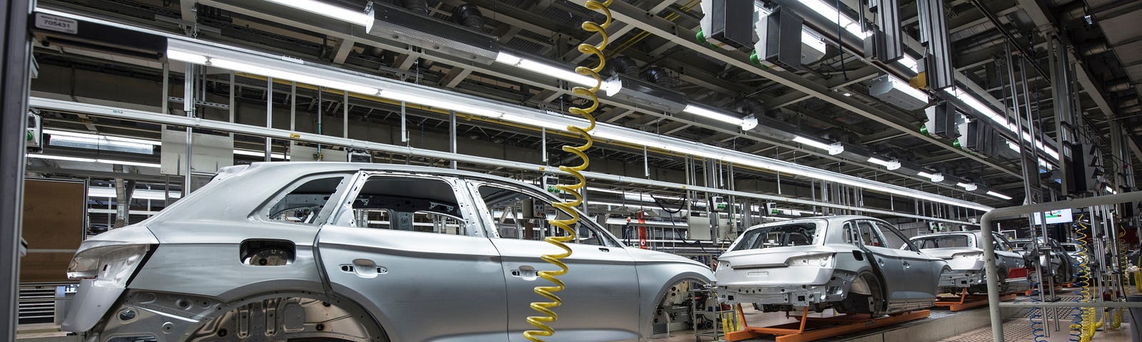 The paint floor in a car factory, with unpainted vehicle chassis on a conveyor belt.