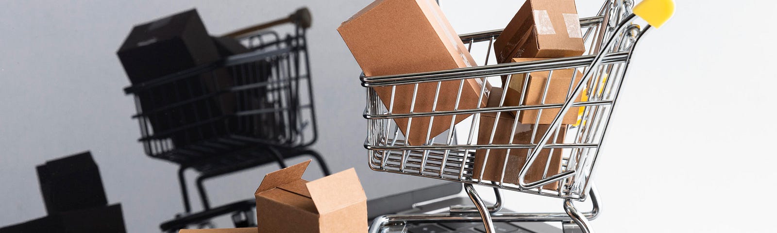 An open notebook in a white background, with a shopping cart full of cardboard boxes standing for the increasing of sales in ecommerce.