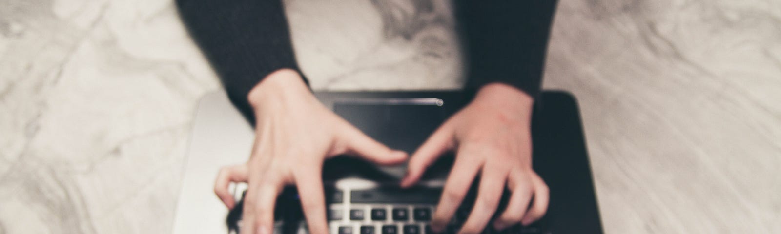 Overhead shot of hands typing on a laptop