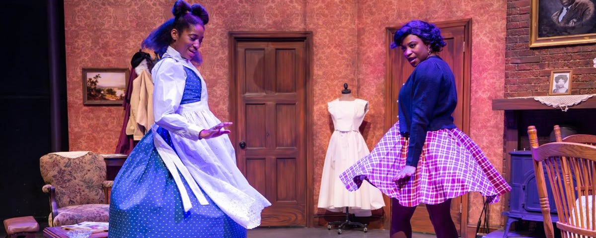 Two women in 1950s dresses dance and twirl