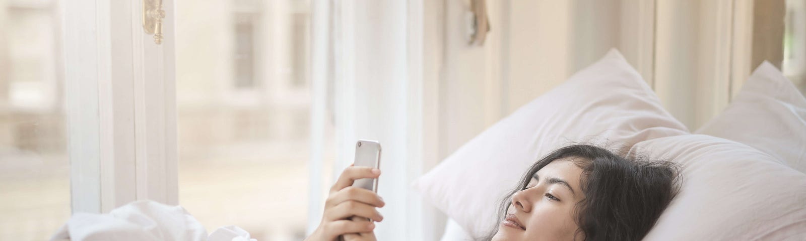 Person in bed looking at their phone, presumably first-thing in the morning.