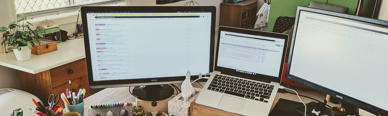 View of a home office desk with a laptop connected to two external monitors.