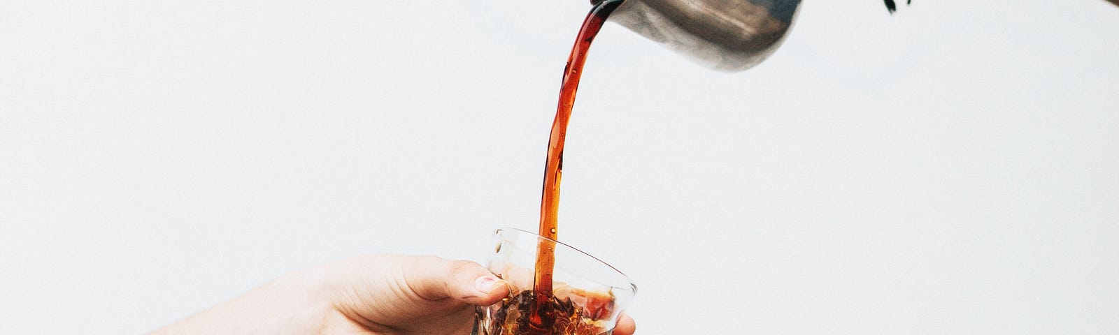 Pouring iced coffee through a cup.