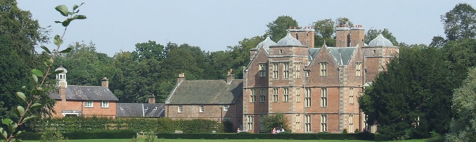 Jacobean Manor house c1620 built of red brick with lake in front.