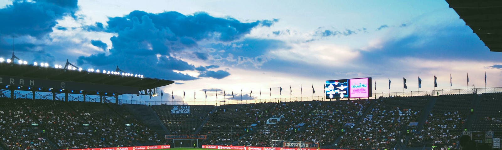 Football pitch with supporters under a foreboding sky