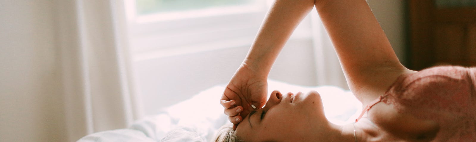 Image of a woman laying on her bed, just woken up.