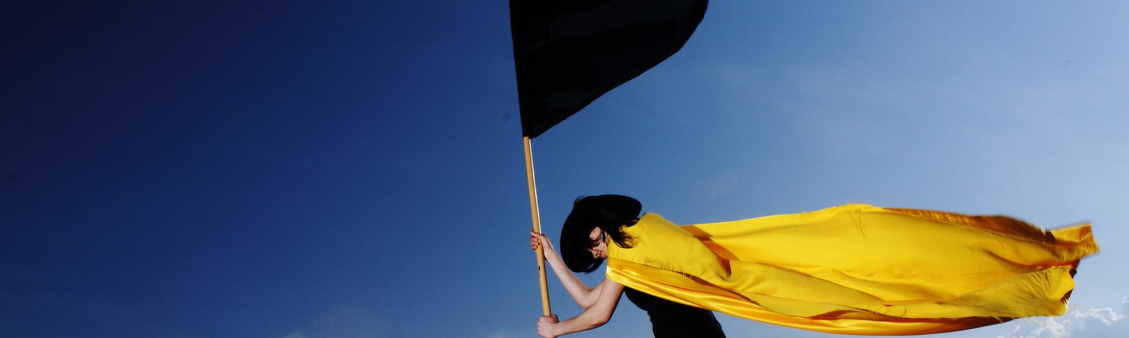 Person in a yellow cap on a boat holding a black flag