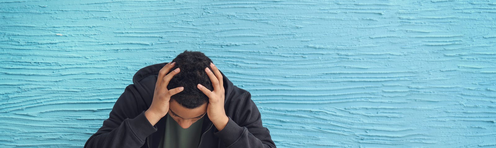 A young man holding his head while sitting down. Leadership