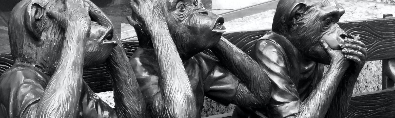 See no evil. Hear no evil. Speak no evil. Three statue monkeys sitting on a bench depict these actions.