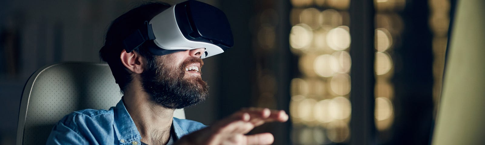 A man wearing virtual reality goggles at his desk.