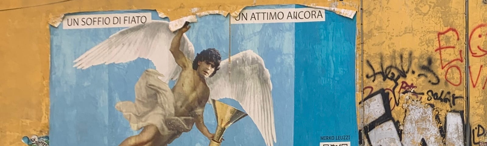 Mural on an outside wall showing Maradona with angel’s wings, surrounded by graffiti.