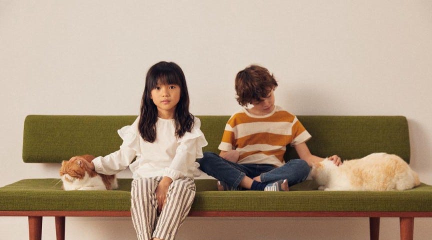 a girl and a boy are sitting on a green couch
