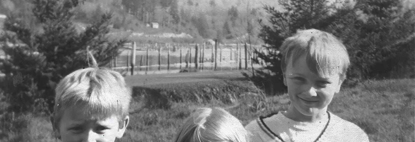 Three kids, ages 6 to 8, posing in front of the Yaquina River.