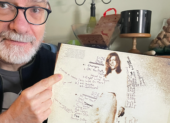 Man pointing at text on the back of a record album that reads, “inspired by Frankie”