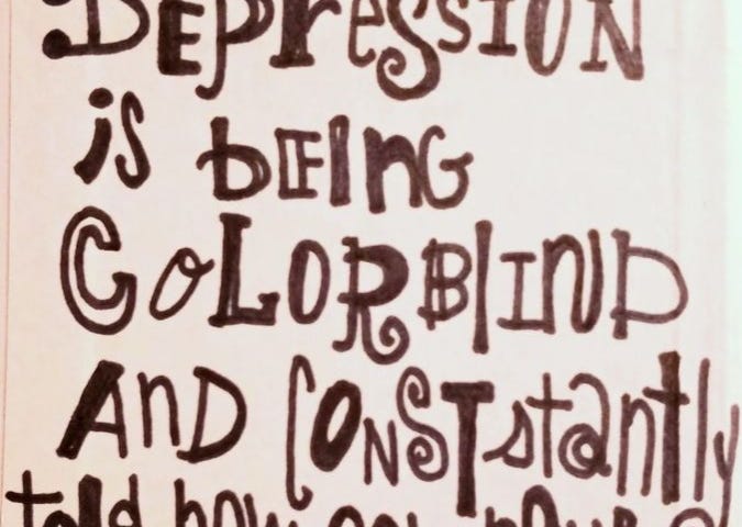 A sign of words written with black marker that says “Depression is being colorblind and constantly told how colorful the world is”