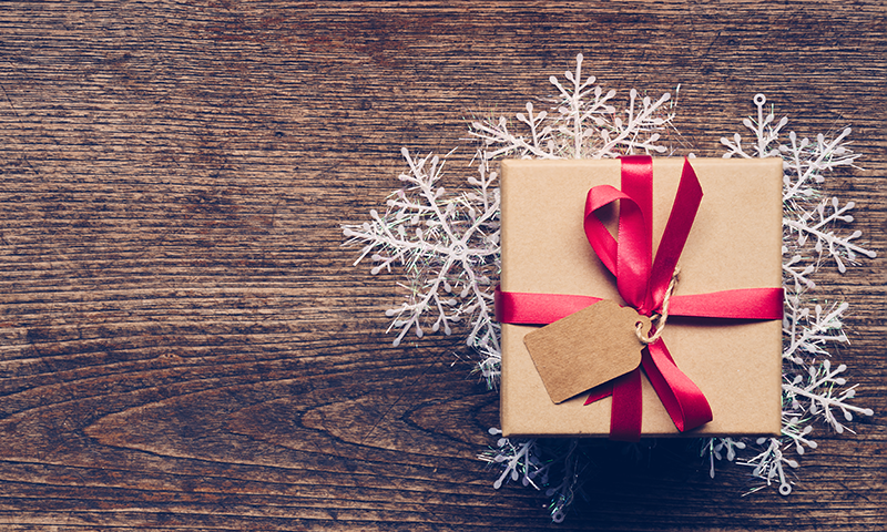 small wrapped gift on a snowflake shaped doily on a wood table.