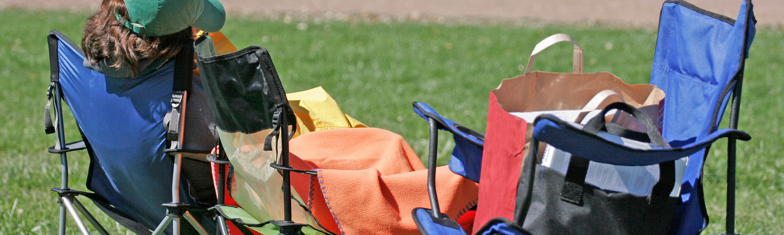 Image from behind of a person in green baseball hat sleeping in fold-up outdoor chairs. There is a trophy graphic superimposed on the image and a text banner reading: “The Stealth Sleeper Award.”