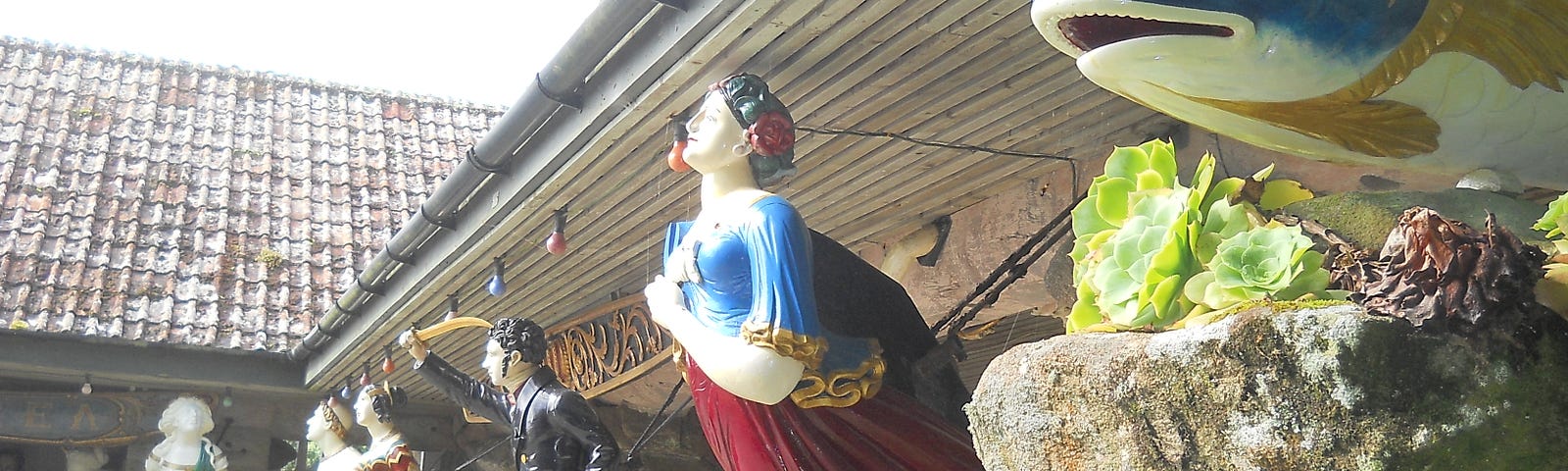 The photograph shows some of the unique and highly decoratively painted carved figureheads of fish, men and women, which were once attached to the bows of sailing ships, and which are now housed in the Valhalla collection situated within Tresco Abbey Garden, Scilly Isles.