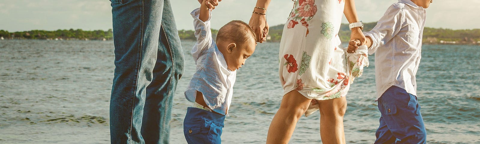 Family with children walking on the beach, holding hands.