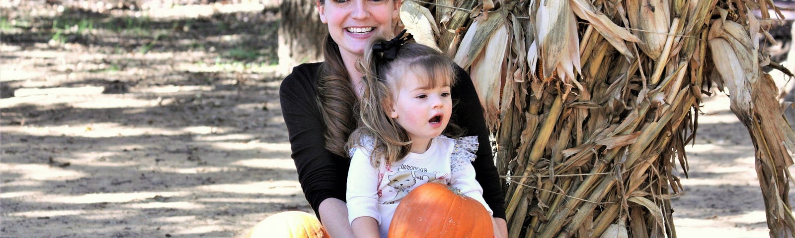 Young woman, mother, with child and pumpkins. Food grown on healthy, living soil can change the world.