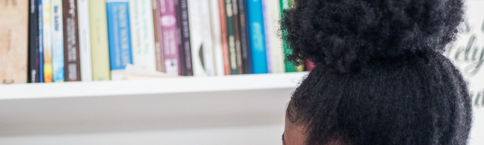 Young black girl chooses book from shelf