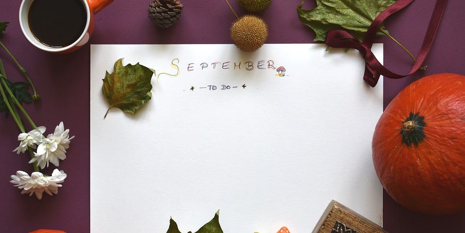 A picture of a sheet of paper with “September” written on it, surrounded by pumpkins and leaves, indicating fall season