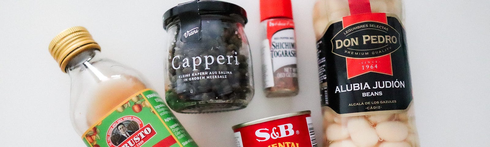 A photo of various items on focus from my pantry—apple cider vinegar, salt-preserved capers, shichimi togarashi, curry powder, and lima beans.