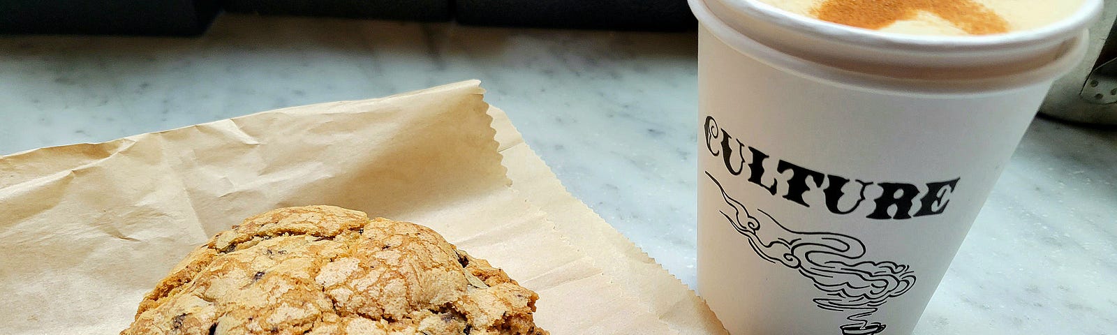 Chocolate chip cookie and coffee drink on marble counter