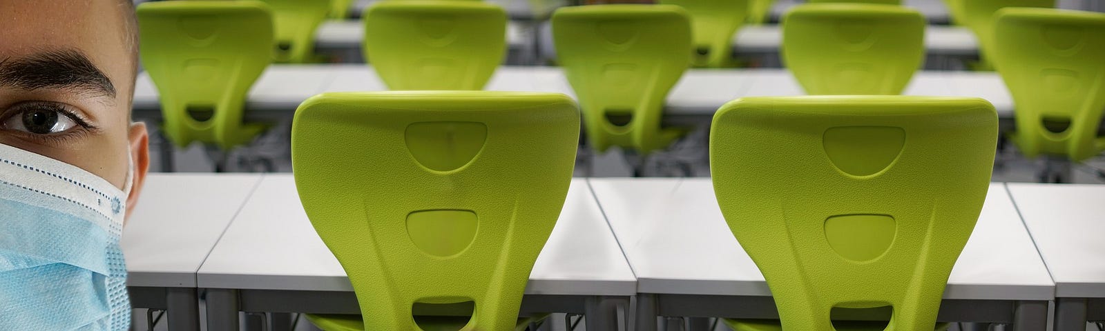 Rows of green chairs behind a person wearing a mask