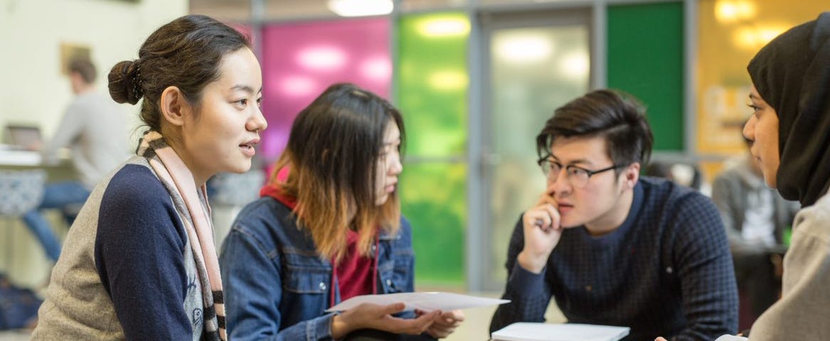 Four students sat at a table with a notepad