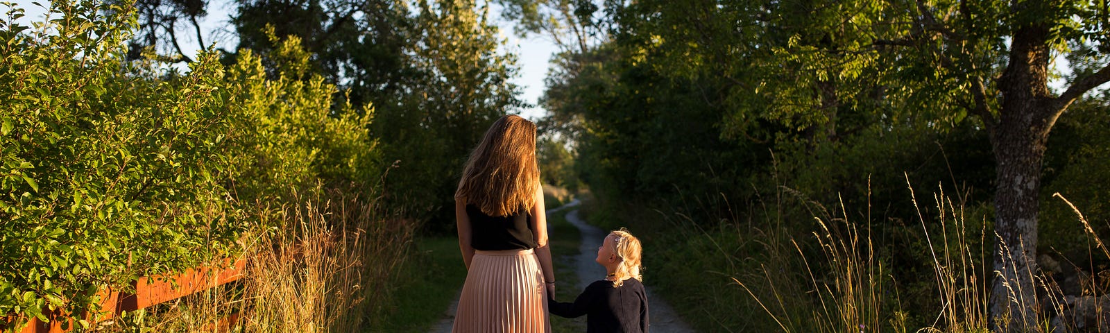 A mother and daughter walking down a dirt path.