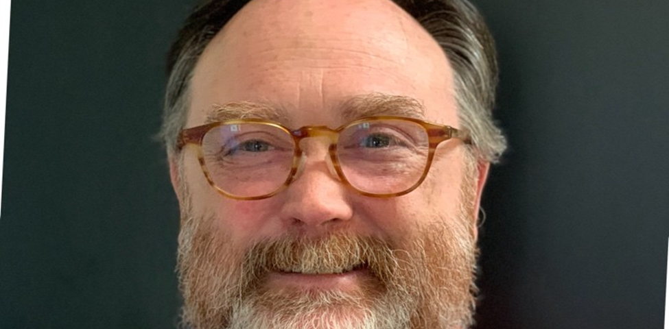 A balding middle-aged man with glasses and a beard.