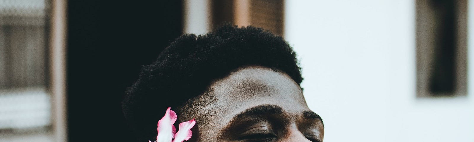 A beautiful Black man with a flower behind his ear.