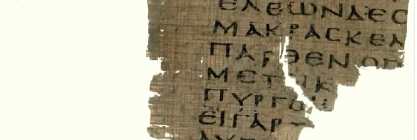 A fragment of ancient parchment with greek lettering is shown against a white background.