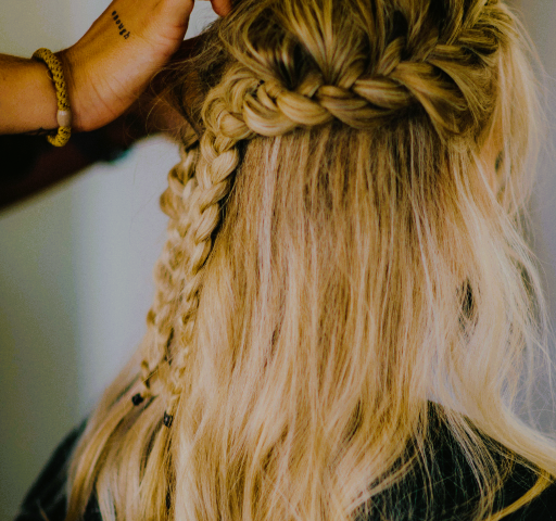 A woman getting her hair done; blond hair with a braid