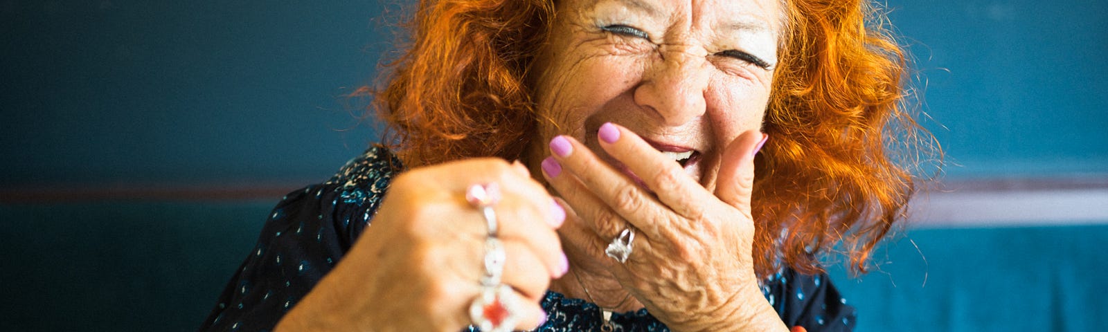 An elegant, redheaded older woman laughing uproariously.