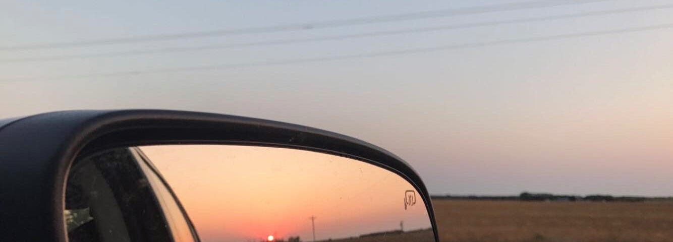 Car mirror reflecting the sunrise