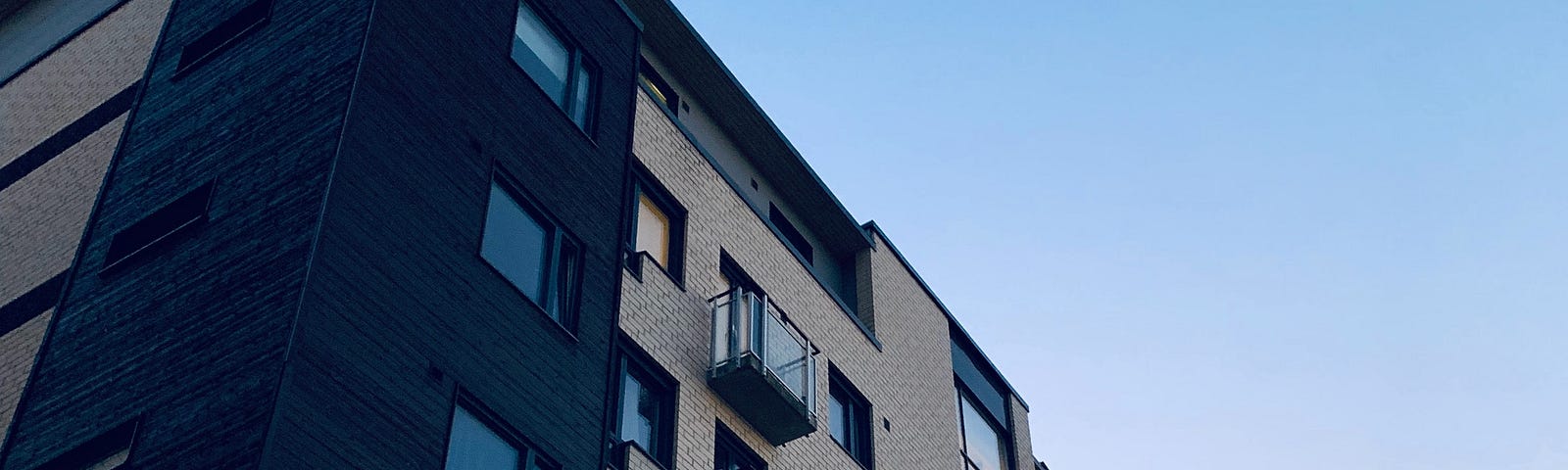 Grey apartment building against blue sky.