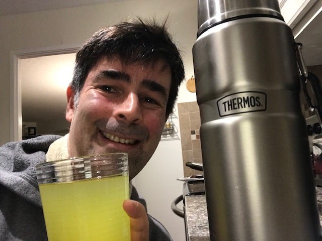 Photo of author with glass of ginger-turmeric tea, along with a thermos of the same.