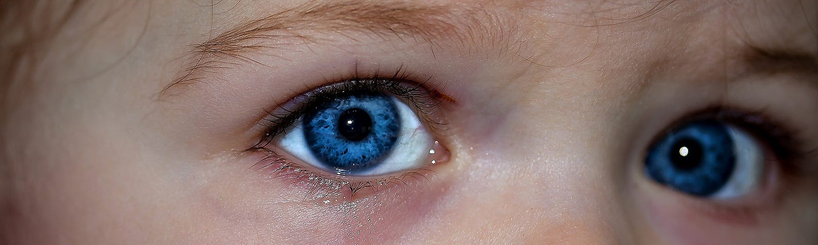 Close up of a baby’s crying blue eyes.