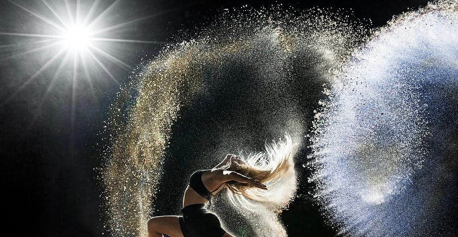 A powerful woman, dancing on the beach, magic showering around her.