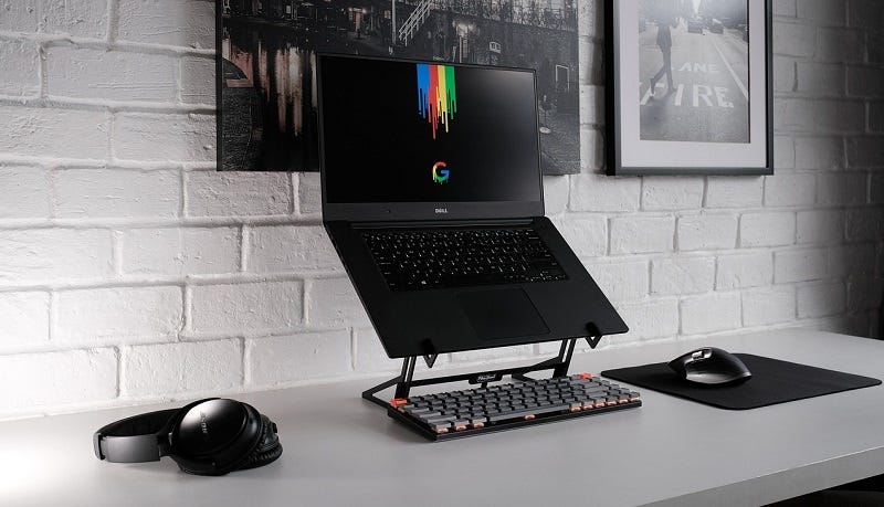 a laptop computer on a stand with a wireless keyboard and mouse