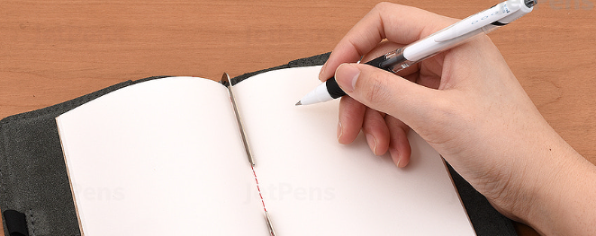 Hand holding a pen over a blank note book