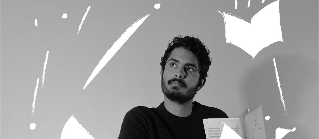 Black and white image of man holding an open book and looking into the distance.