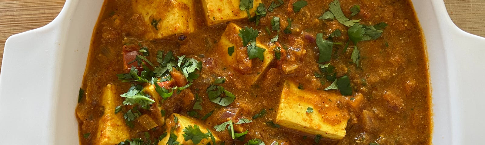 Paneer butter masala curry garnished with coriander leaves.