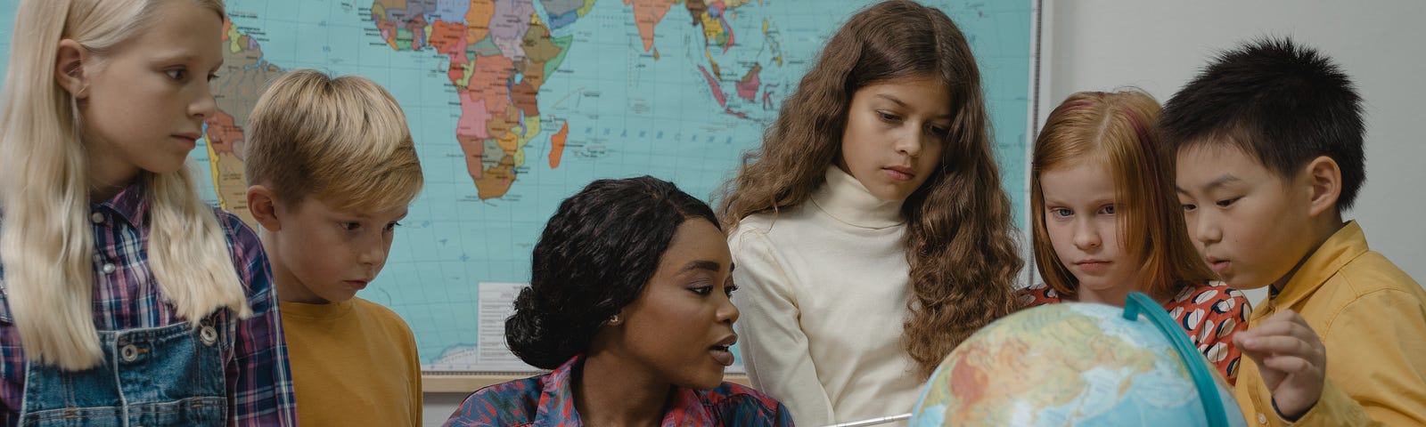 Teacher with students pointing to countries on a globe