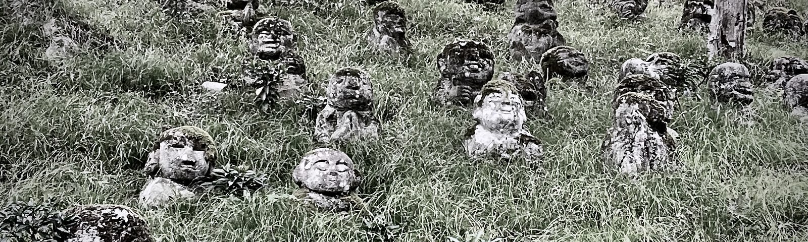 Several stone Buddhist statuettes called Jizo (geez-oh) on a grassy slope in Kyoto, Japan.