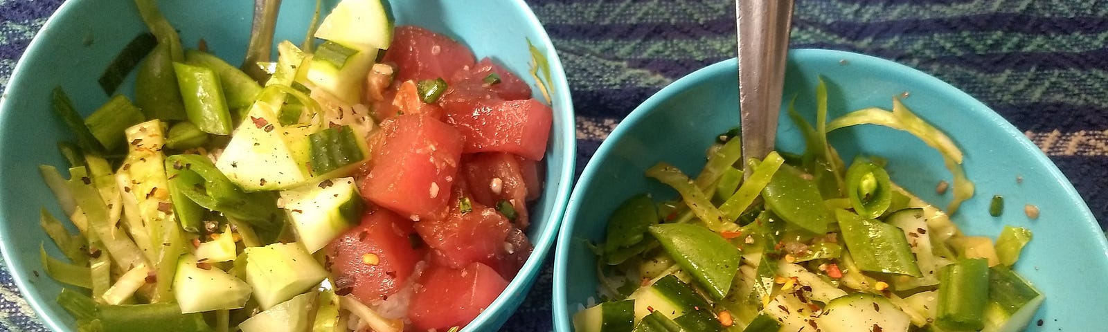 Two bowls of poke with tuna, rice, and mixed raw vegetables.