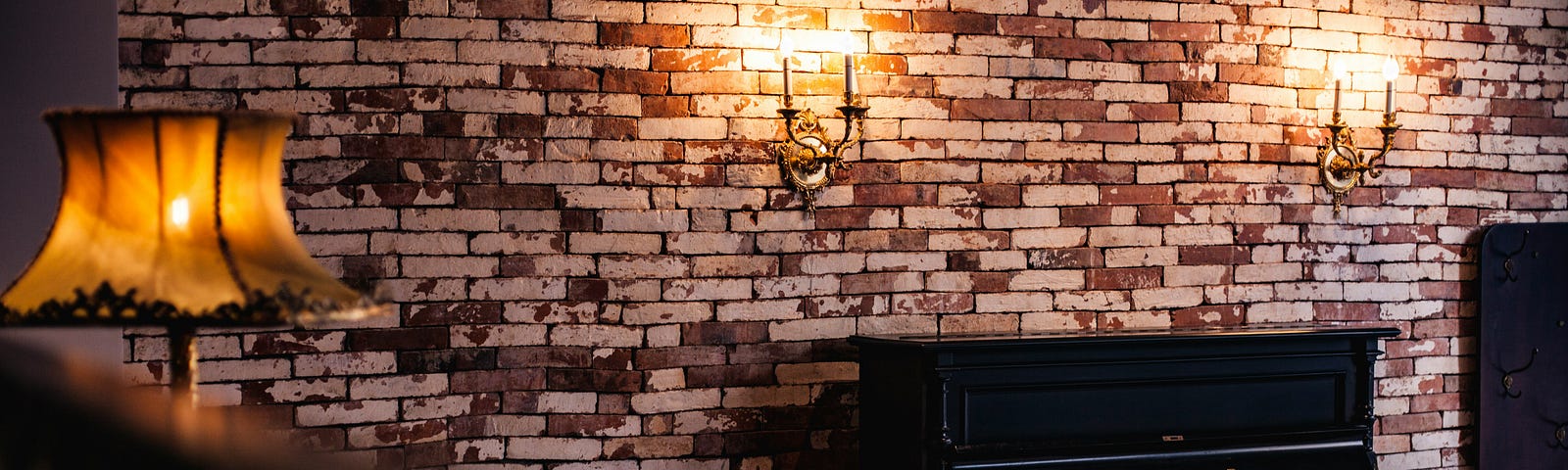 Old black piano, with candle lamps on a brick wall